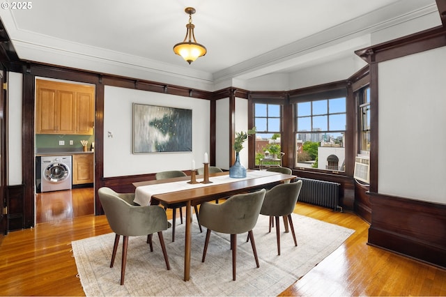 2083 NW Johnson St Unit 45, Portland, OR 97209 - dining space with washer / clothes dryer, radiator heating unit, light wood-type flooring, crown molding, and bar