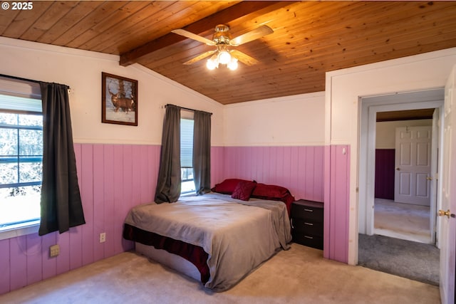 carpeted bedroom with ceiling fan, vaulted ceiling with beams, wood ceiling, and wainscoting