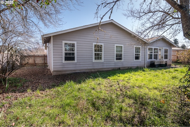 rear view of property with a yard, fence, and central AC