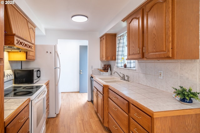 kitchen with white electric range oven, tile countertops, light wood-style flooring, a sink, and stainless steel dishwasher