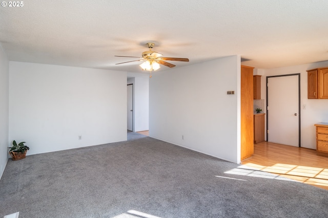 unfurnished room with light colored carpet, a textured ceiling, and ceiling fan