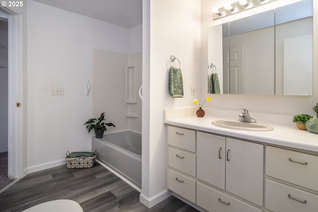 bathroom featuring baseboards, toilet, shower / bathing tub combination, wood finished floors, and vanity