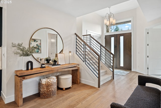 entrance foyer with a notable chandelier, stairway, baseboards, and wood finished floors