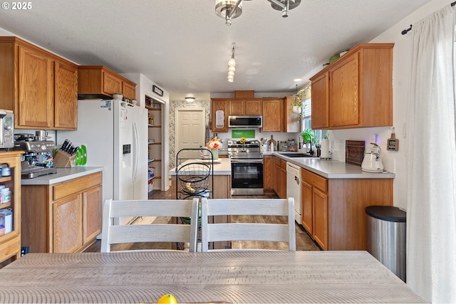 kitchen featuring light countertops, a sink, appliances with stainless steel finishes, and brown cabinets