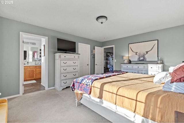 bedroom featuring baseboards, light carpet, ensuite bathroom, and a closet
