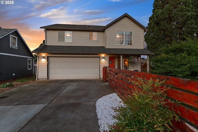 traditional-style home with roof with shingles, an attached garage, and concrete driveway