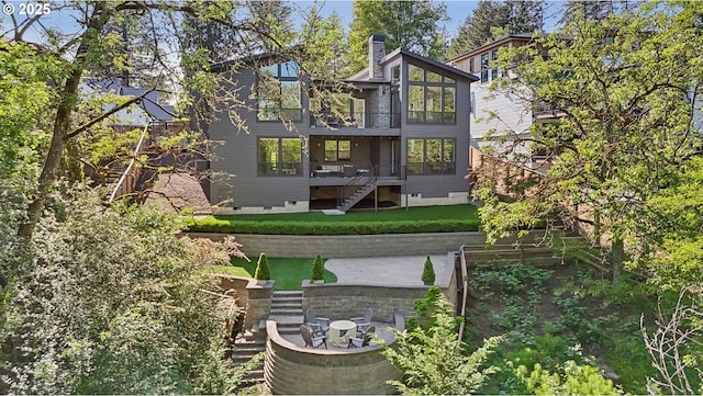 back of house with stairs, crawl space, a deck, and a lawn