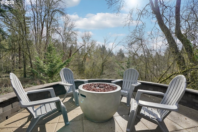 view of patio / terrace with an outdoor fire pit and a view of trees