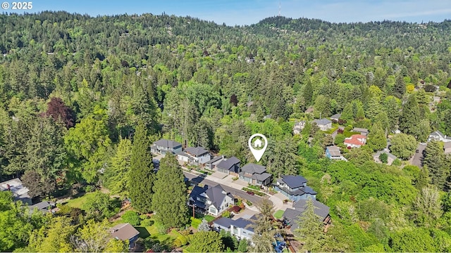 aerial view of property's location featuring a forest and nearby suburban area