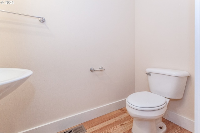 bathroom featuring visible vents, wood finished floors, toilet, and baseboards