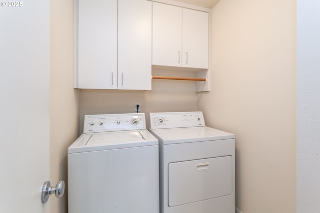 clothes washing area featuring washing machine and dryer and cabinet space