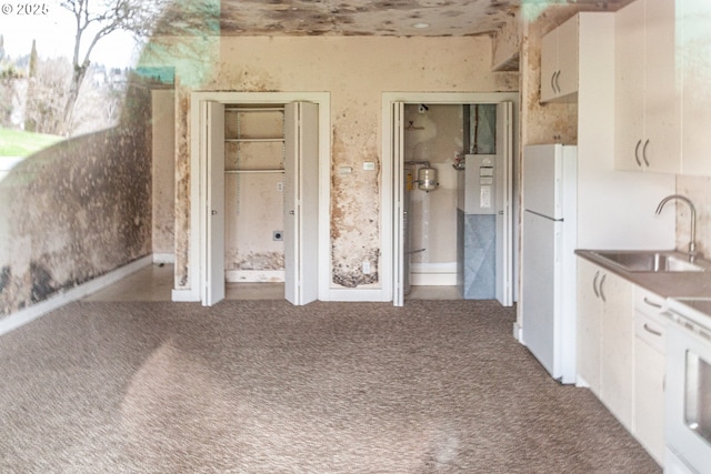 kitchen with white appliances, carpet flooring, a sink, and white cabinetry