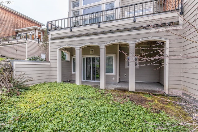 view of exterior entry featuring a patio area and a balcony