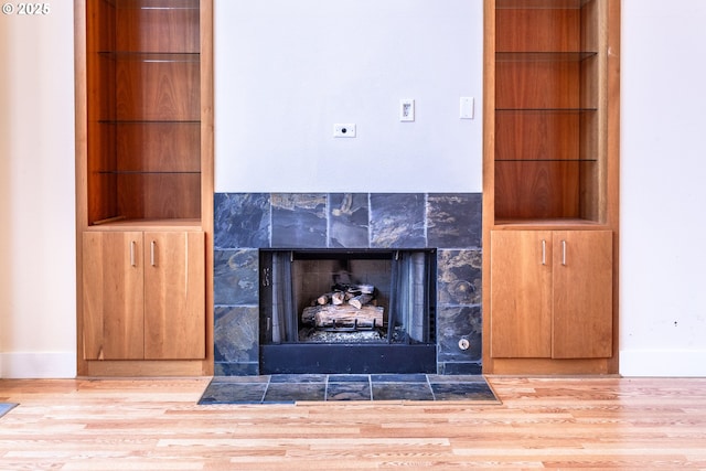 interior details with baseboards, wood finished floors, and a tile fireplace