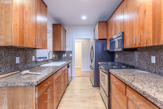 kitchen featuring appliances with stainless steel finishes, a sink, and brown cabinets