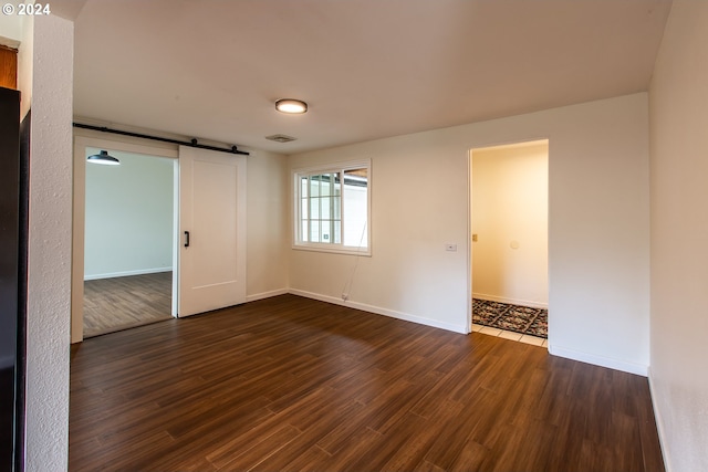 127 Roan Dr, Eugene, OR 97401 - empty room featuring a barn door, dark wood finished floors, and baseboards