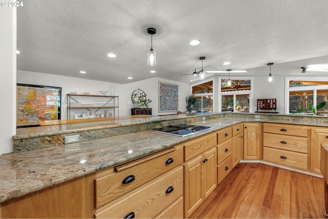 kitchen featuring light stone counters, light wood-style flooring, hanging light fixtures, vaulted ceiling, and black electric stovetop