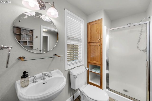 bathroom featuring a sink, toilet, and a stall shower