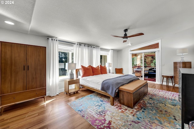 bedroom with a textured ceiling, wood finished floors, vaulted ceiling, and access to exterior