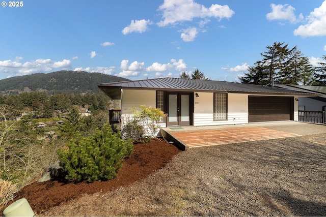 213 University Ave, Manzanita, OR 97130 - view of front of house with covered porch, metal roof, an attached garage, a mountain view, and concrete driveway