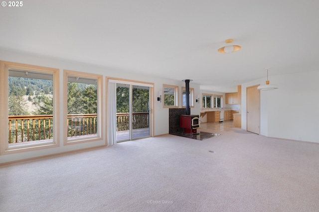 213 University Ave, Manzanita, OR 97130 - unfurnished living room with a wood stove, carpet flooring, and a healthy amount of sunlight