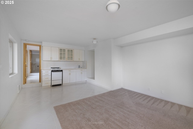 213 University Ave, Manzanita, OR 97130 - interior space with baseboards, white stove, glass insert cabinets, light tile patterned flooring, and white cabinets