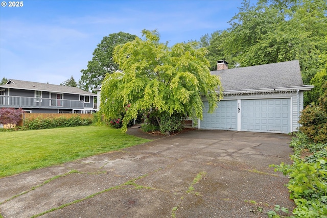view of front of property featuring asphalt driveway, a chimney, a front yard, and a garage