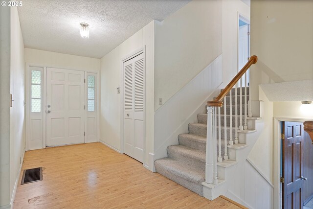 foyer featuring wood finished floors, a textured ceiling, and stairs