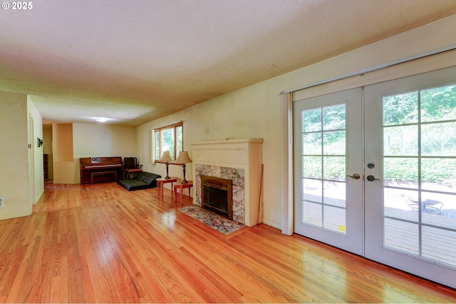 6620 SE Barbara Welch Rd, Portland, OR 97236 - living area with light wood-type flooring, french doors, a high end fireplace, and a textured ceiling