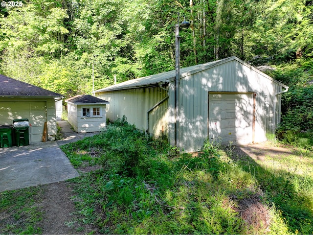 6620 SE Barbara Welch Rd, Portland, OR 97236 - view of side of property featuring an outdoor structure, a detached garage, and a forest view