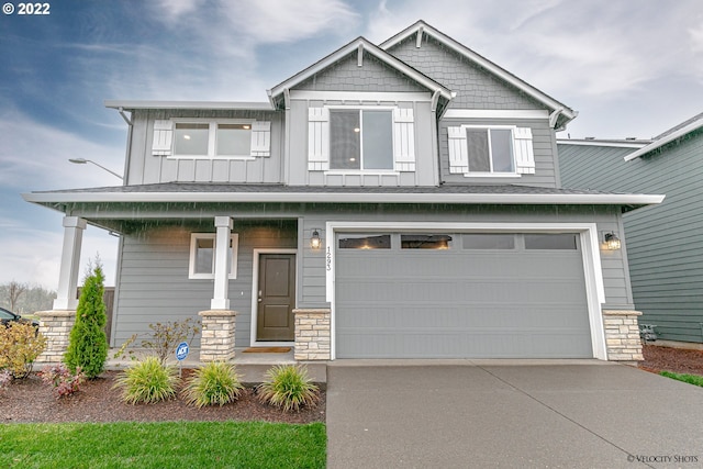 craftsman inspired home with an attached garage, covered porch, concrete driveway, stone siding, and board and batten siding