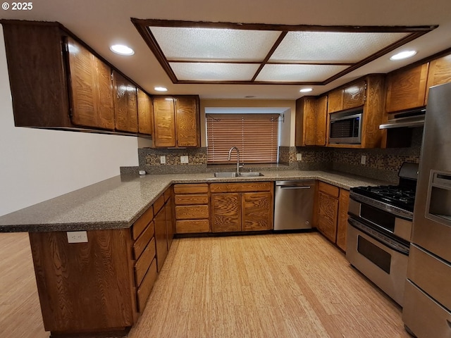 kitchen featuring kitchen peninsula, sink, tasteful backsplash, and stainless steel appliances