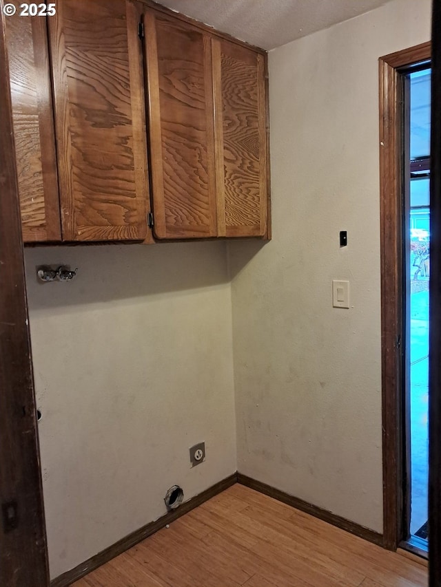 laundry area with cabinets, hookup for an electric dryer, and light wood-type flooring