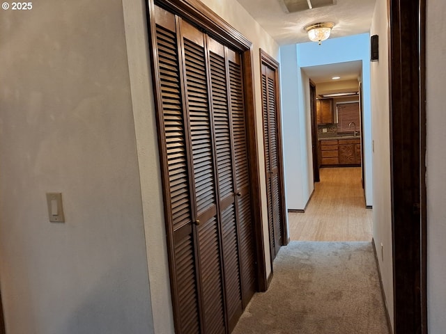 hall with light colored carpet and sink