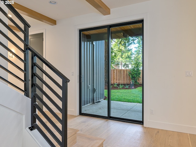 doorway to outside with beamed ceiling, baseboards, light wood-style floors, and stairs