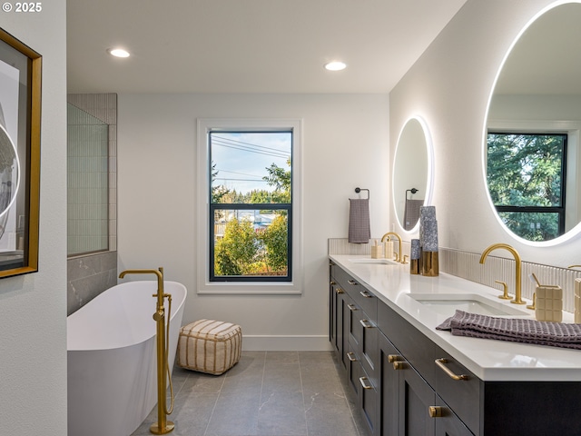 full bath featuring a freestanding tub, plenty of natural light, and a sink