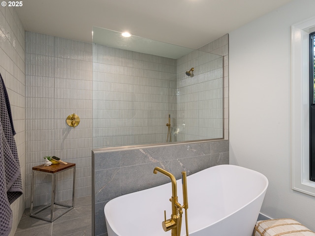 bathroom featuring tile walls, a walk in shower, and a freestanding bath