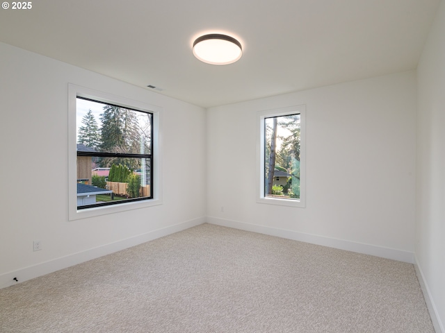 spare room with visible vents, light colored carpet, and baseboards