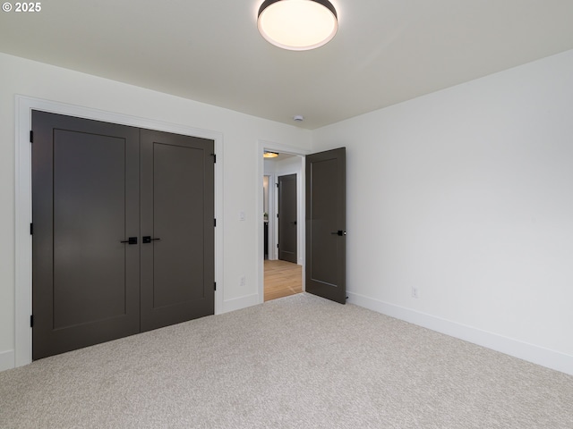 unfurnished bedroom with baseboards, carpet floors, and a closet