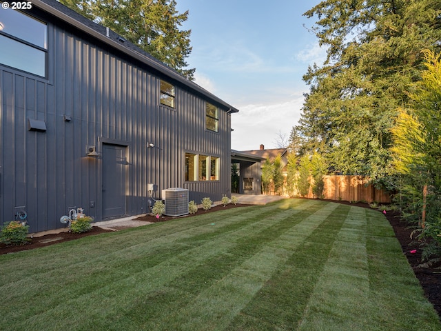 rear view of property featuring a patio, fence, a lawn, and board and batten siding