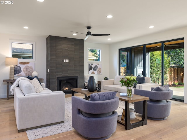 living area featuring recessed lighting, a fireplace, light wood-style floors, and a ceiling fan