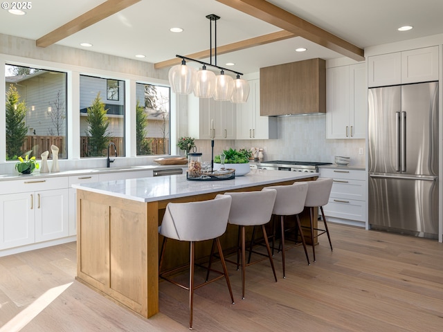 kitchen featuring custom range hood, a center island, stainless steel appliances, a breakfast bar area, and light wood finished floors