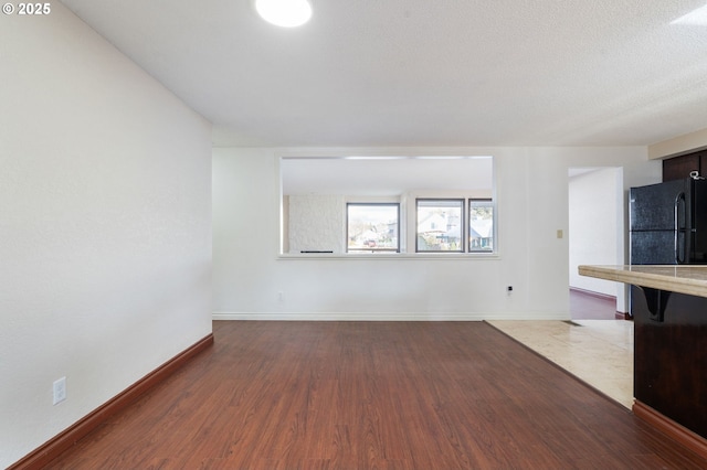 unfurnished living room with wood finished floors and baseboards