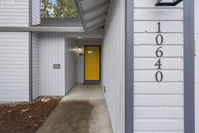 doorway to property featuring roof with shingles