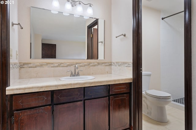 bathroom featuring decorative backsplash, toilet, vanity, and a tile shower