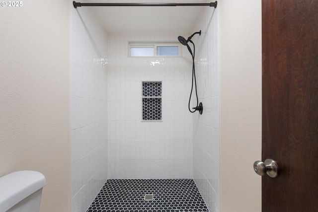 full bath with a tile shower and toilet