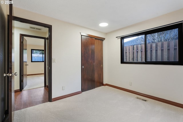 unfurnished bedroom featuring a closet, visible vents, baseboards, and carpet floors