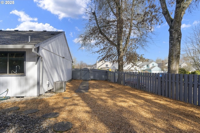 view of yard with cooling unit, fence, and a gate