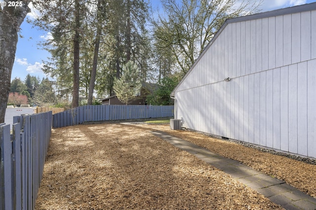 view of yard with central air condition unit and fence