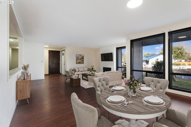 dining space with visible vents, a fireplace, baseboards, and wood finished floors